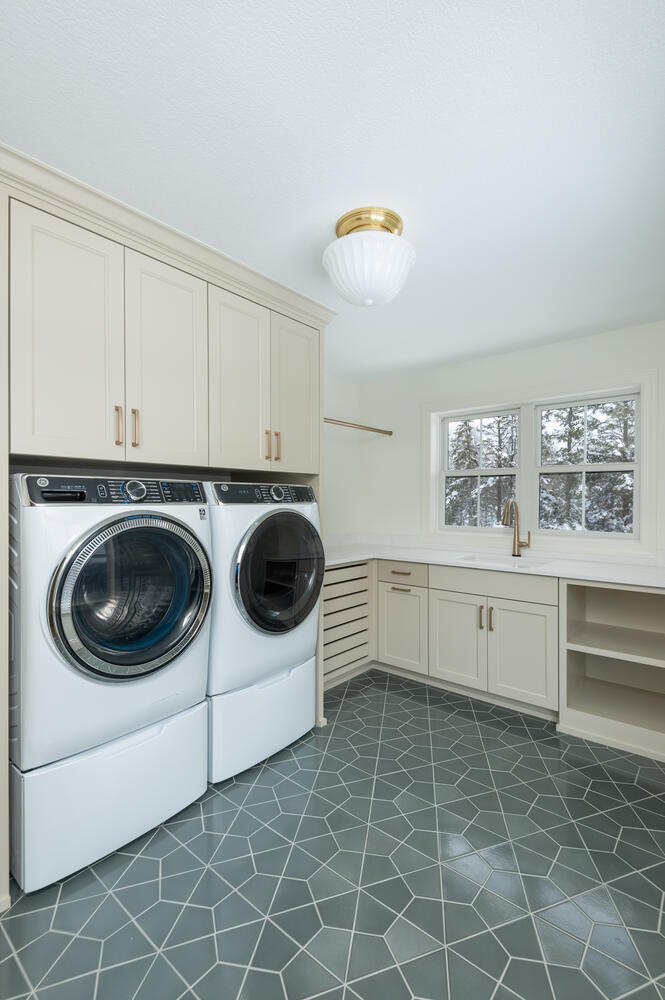 Warm, modern laundry room with teal tile and beige cabinets